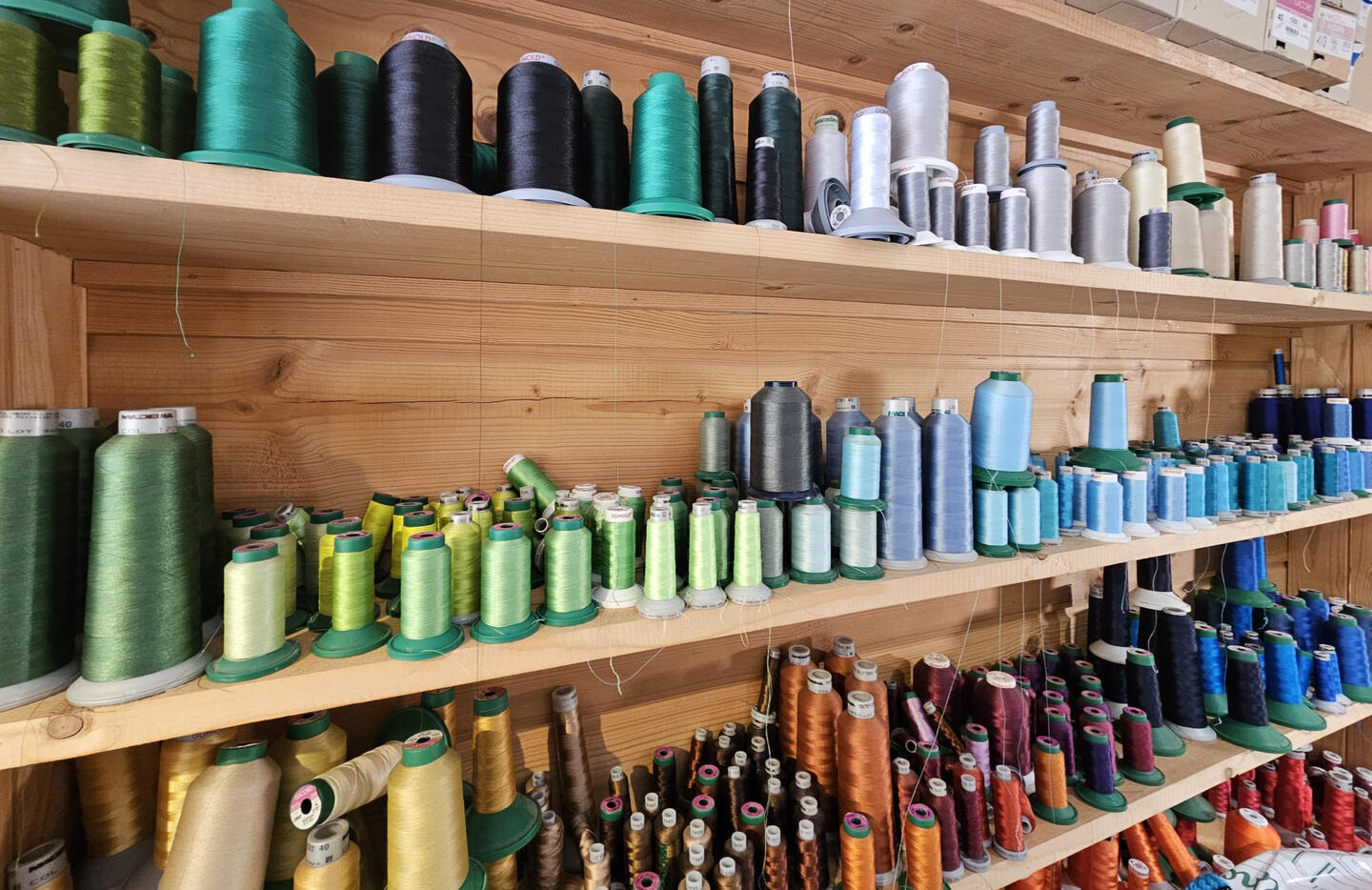 Mur de bobines de fils de broderie dans toutes les teintes — atelier Fastnett